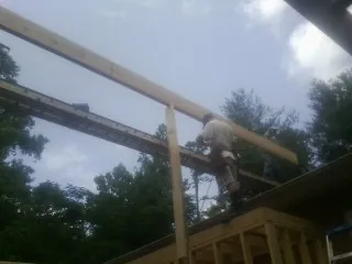 Carpenter setting a ridge beam over a new addition frame — Ice Dam Removal by Roofing Brothers in Camden